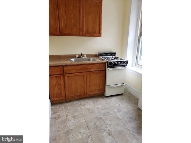 kitchen featuring sink, gas range gas stove, and light tile floors