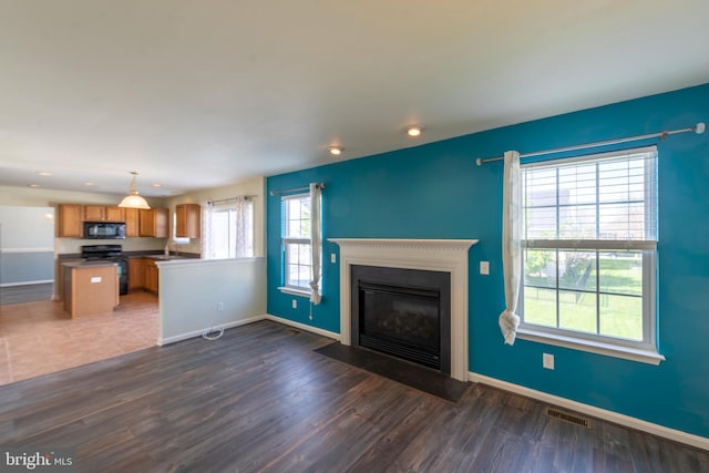 unfurnished living room featuring a wealth of natural light and dark hardwood / wood-style flooring