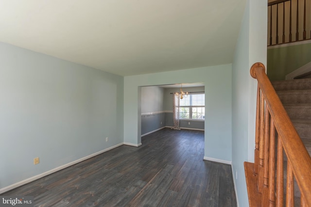 spare room featuring dark wood-type flooring and a notable chandelier