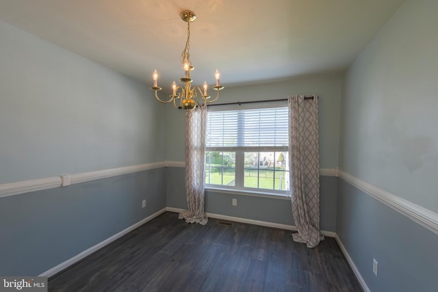 empty room featuring a chandelier and dark hardwood / wood-style floors