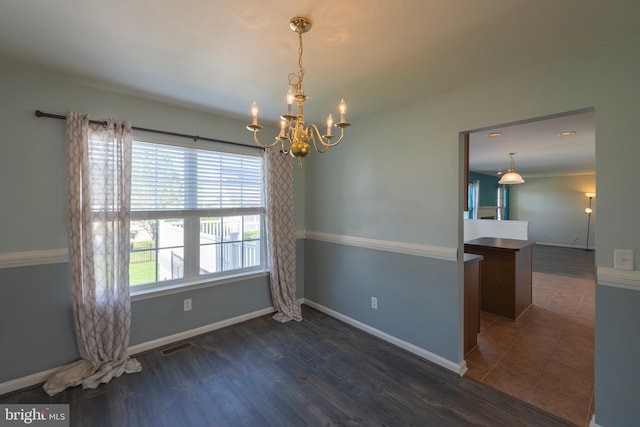 unfurnished room featuring dark tile floors and an inviting chandelier