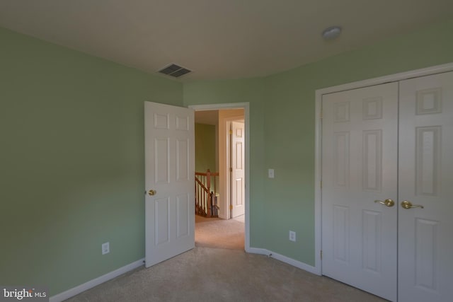 unfurnished bedroom with light carpet and a closet