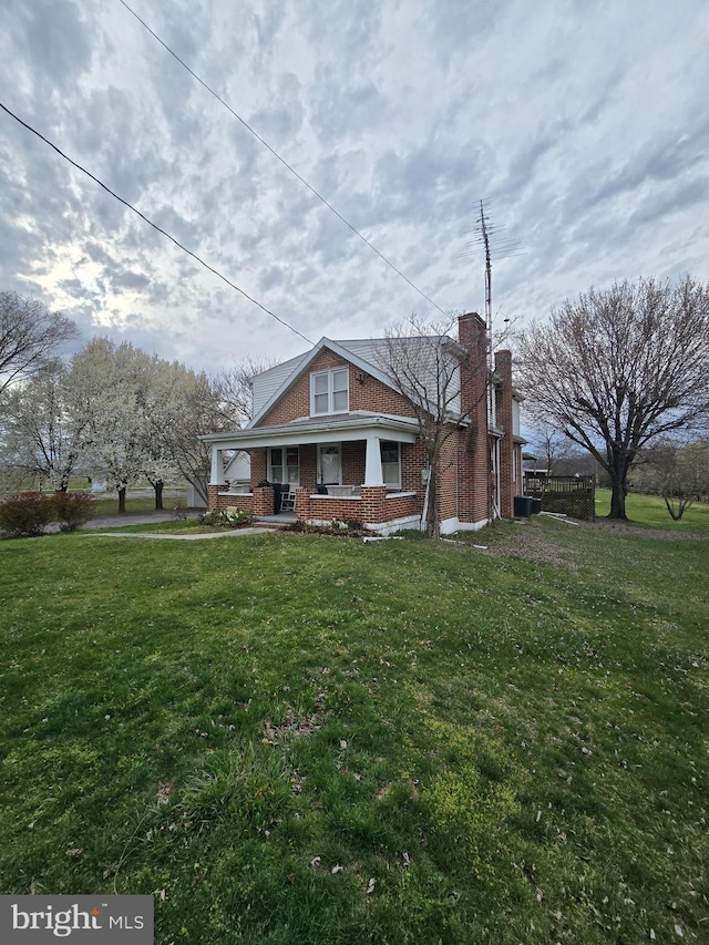 rear view of property with central air condition unit and a yard