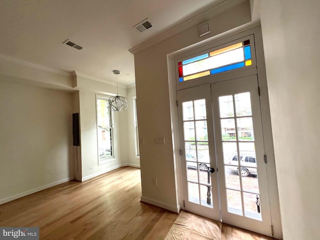 entryway featuring french doors, plenty of natural light, ornamental molding, and light hardwood / wood-style flooring