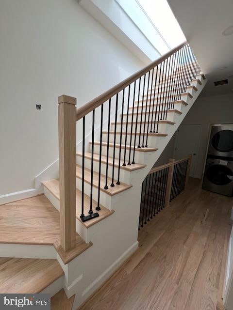 staircase featuring hardwood / wood-style floors and stacked washer and dryer