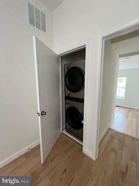 laundry room with hardwood / wood-style floors and stacked washer / drying machine