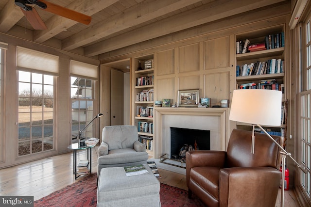 living area featuring built in shelves, beam ceiling, hardwood / wood-style floors, and wooden ceiling