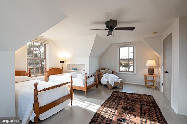 bedroom featuring lofted ceiling, ceiling fan, multiple windows, and light wood-type flooring