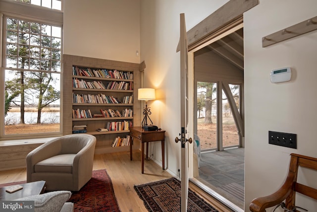 sitting room featuring plenty of natural light, light hardwood / wood-style flooring, french doors, and a water view