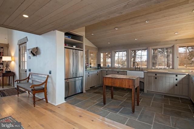 kitchen featuring sink, stainless steel refrigerator, vaulted ceiling, and wooden ceiling