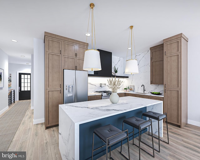 kitchen featuring appliances with stainless steel finishes, a kitchen breakfast bar, hanging light fixtures, light hardwood / wood-style flooring, and a center island