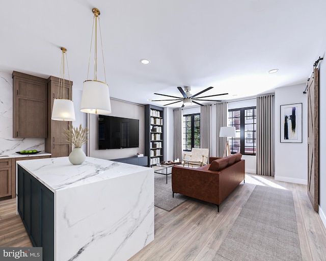 living room featuring ceiling fan, a barn door, and light hardwood / wood-style floors