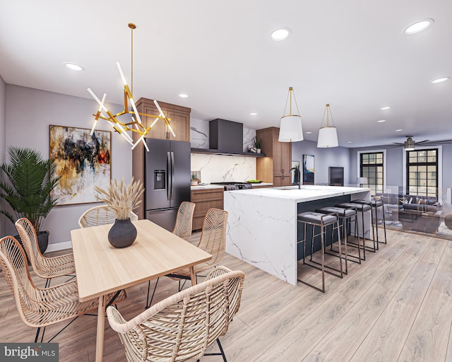 kitchen featuring an island with sink, stainless steel fridge with ice dispenser, and light wood-type flooring