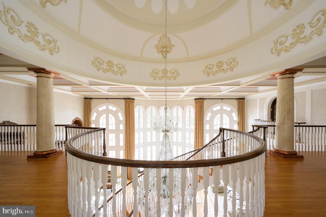 hall with hardwood / wood-style floors, coffered ceiling, decorative columns, and a chandelier