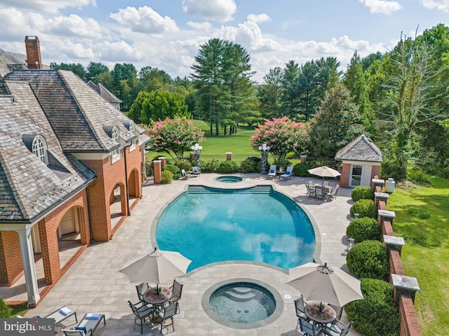 view of swimming pool with a patio, a lawn, and an in ground hot tub