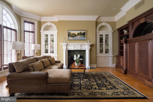 living room featuring a wealth of natural light, crown molding, light hardwood / wood-style flooring, and a fireplace