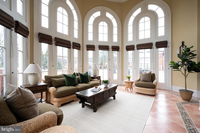 living room featuring a towering ceiling, light tile floors, and a healthy amount of sunlight