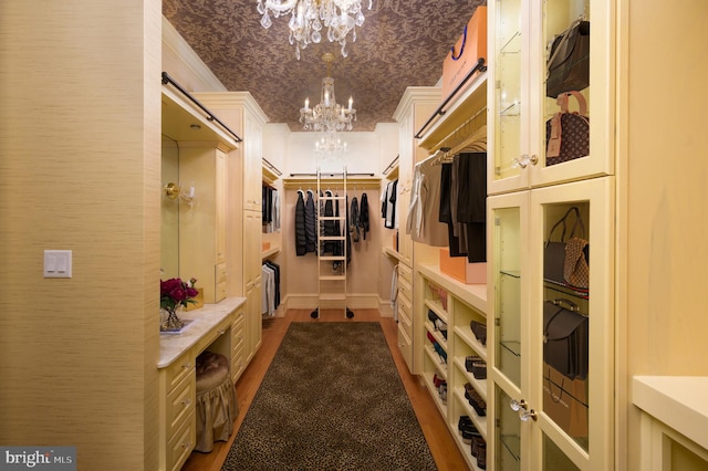 walk in closet with dark wood-type flooring and a chandelier