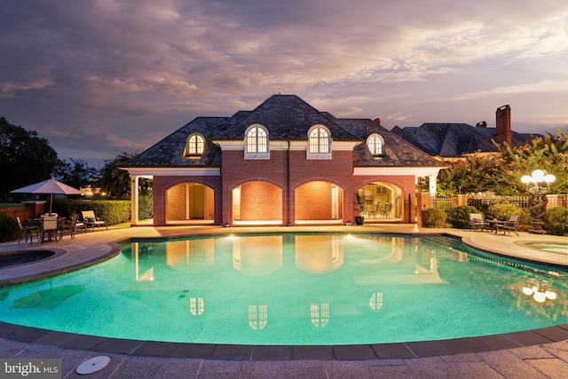 pool at dusk featuring a patio area