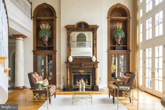 sitting room featuring french doors, a high ceiling, light hardwood / wood-style floors, and plenty of natural light