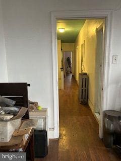 corridor with dark hardwood / wood-style flooring and radiator