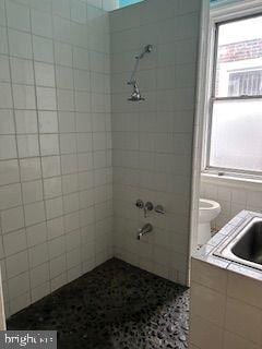 bathroom with tile walls, tile floors, toilet, and sink