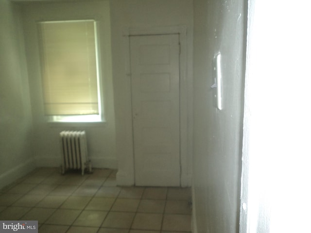 corridor featuring light tile patterned floors and radiator