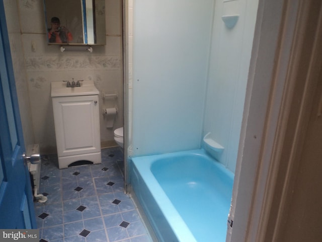 bathroom featuring tile patterned flooring, vanity, toilet, and a tub