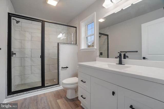 bathroom featuring a shower with shower door, hardwood / wood-style flooring, toilet, and vanity