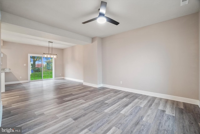 empty room featuring wood-type flooring and ceiling fan with notable chandelier