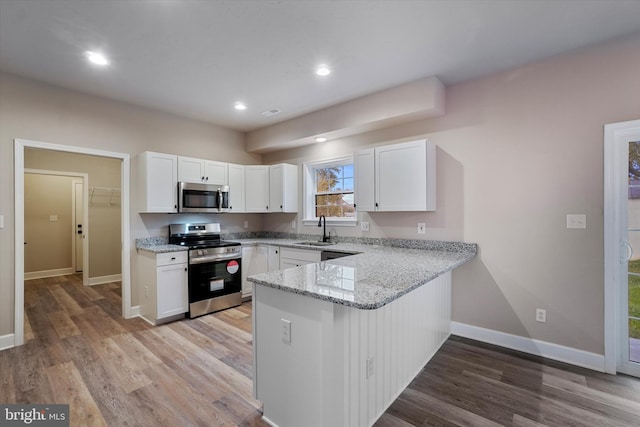 kitchen with appliances with stainless steel finishes, light stone countertops, and white cabinetry