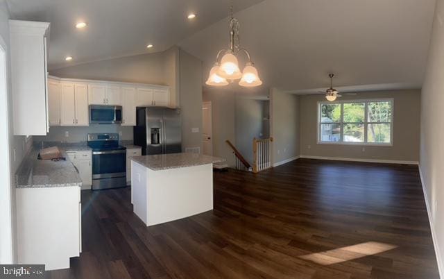 kitchen featuring white cabinetry, light stone countertops, a kitchen island, ceiling fan with notable chandelier, and appliances with stainless steel finishes