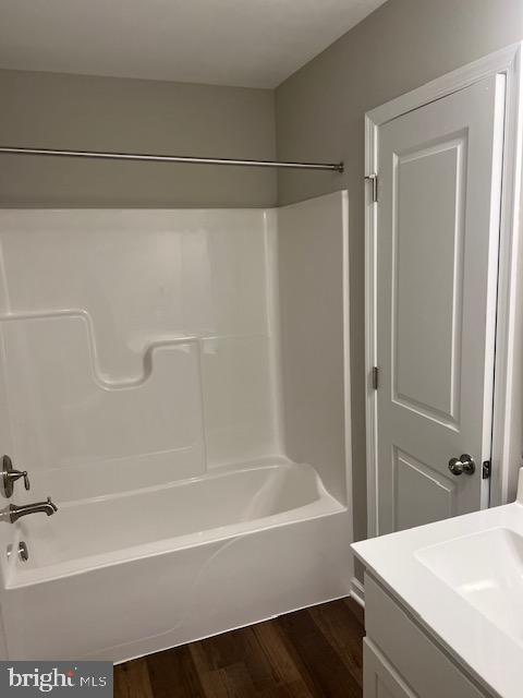 bathroom with hardwood / wood-style flooring, vanity, and bathing tub / shower combination