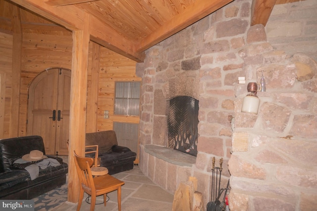 living room featuring a fireplace, wood walls, wood ceiling, and beamed ceiling