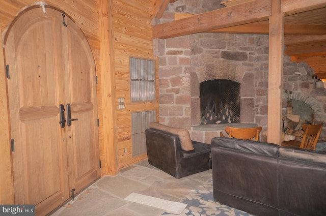 living room featuring wooden walls, a stone fireplace, and light tile floors