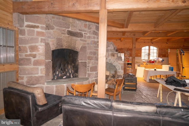 living room with wood walls, a stone fireplace, wood ceiling, and beamed ceiling