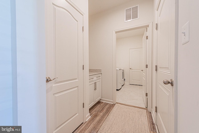 hallway with light hardwood / wood-style flooring and independent washer and dryer