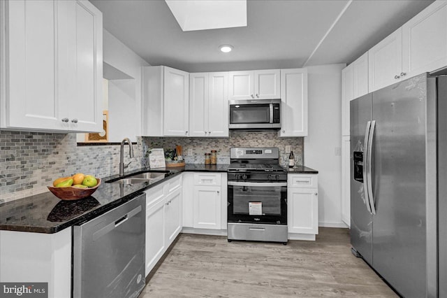 kitchen featuring appliances with stainless steel finishes, light hardwood / wood-style floors, white cabinets, backsplash, and sink