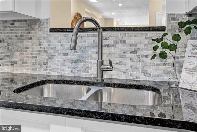 kitchen featuring backsplash, sink, white cabinetry, and dark stone countertops