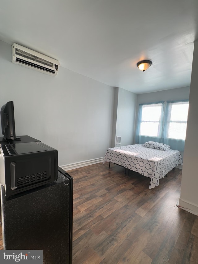 bedroom with dark hardwood / wood-style floors and a wall mounted air conditioner