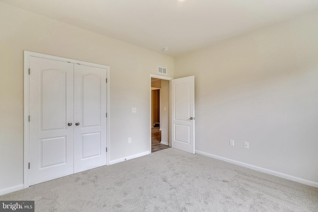 unfurnished bedroom featuring light colored carpet and a closet