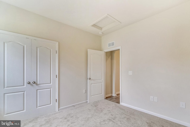 unfurnished bedroom with a closet and light colored carpet