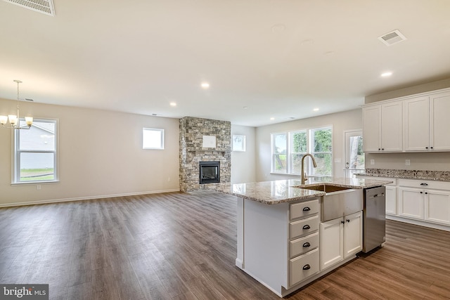 kitchen featuring hanging light fixtures, dark wood-type flooring, a fireplace, a notable chandelier, and stainless steel dishwasher