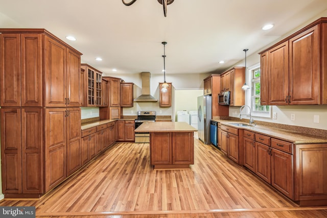 kitchen featuring a center island, wall chimney exhaust hood, independent washer and dryer, pendant lighting, and appliances with stainless steel finishes