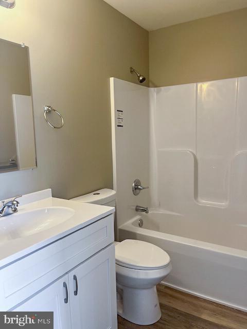 full bathroom with hardwood / wood-style floors, toilet, shower / bathing tub combination, and vanity