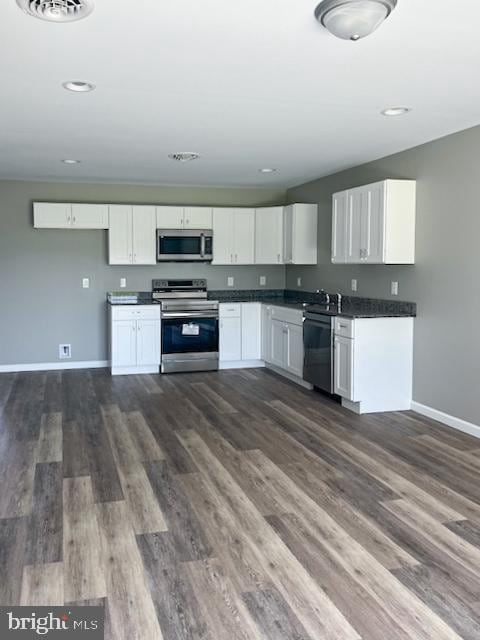 kitchen with white cabinetry, stainless steel appliances, sink, and dark hardwood / wood-style floors