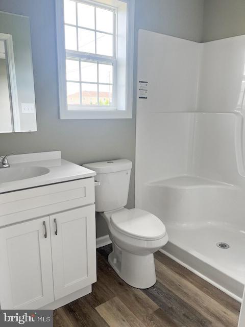 bathroom featuring vanity, toilet, hardwood / wood-style flooring, and walk in shower