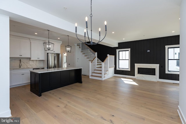 kitchen with a kitchen island, light hardwood / wood-style flooring, stainless steel refrigerator, an inviting chandelier, and decorative light fixtures