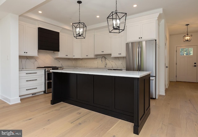 kitchen featuring appliances with stainless steel finishes, hanging light fixtures, a kitchen island, light hardwood / wood-style flooring, and white cabinets