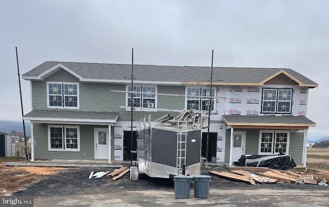 property in mid-construction featuring roof with shingles